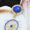 Piercing nombril plaqu� or et bleu � barre (roue) de bateau