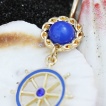 Piercing nombril plaqu� or et bleu � barre (roue) de bateau